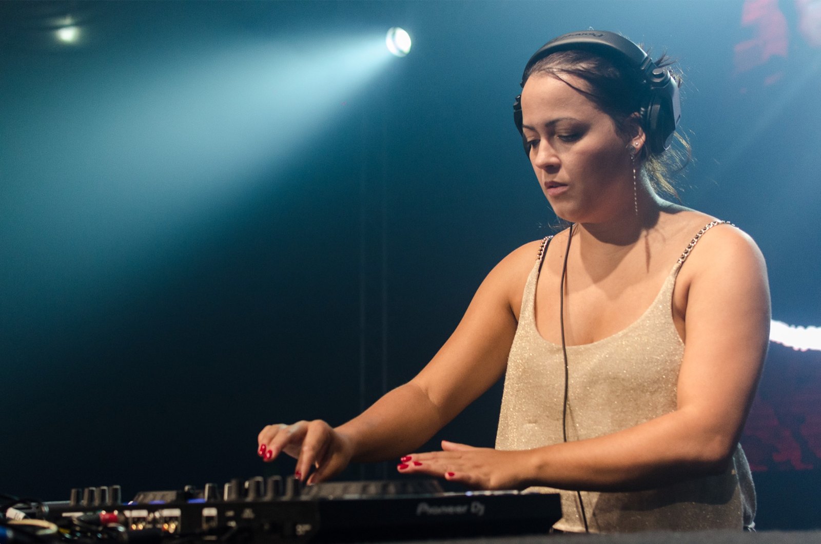 DJ operando a controladora em um evento com iluminação cênica, produzido pela MAC2